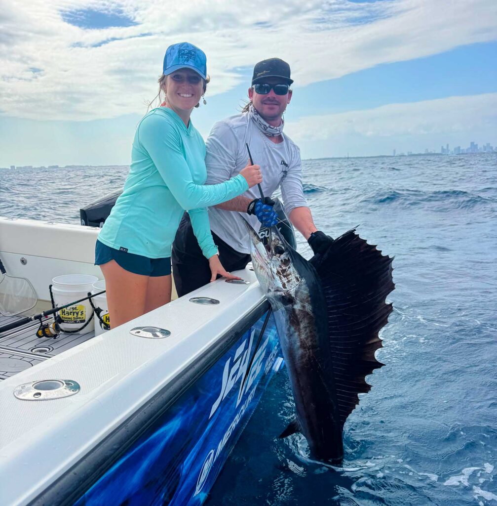 Female angler releasing sailfish with Miami skyline in the background.
