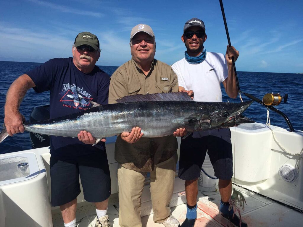 Angler holding a big wahoo caught high speed trolling.
