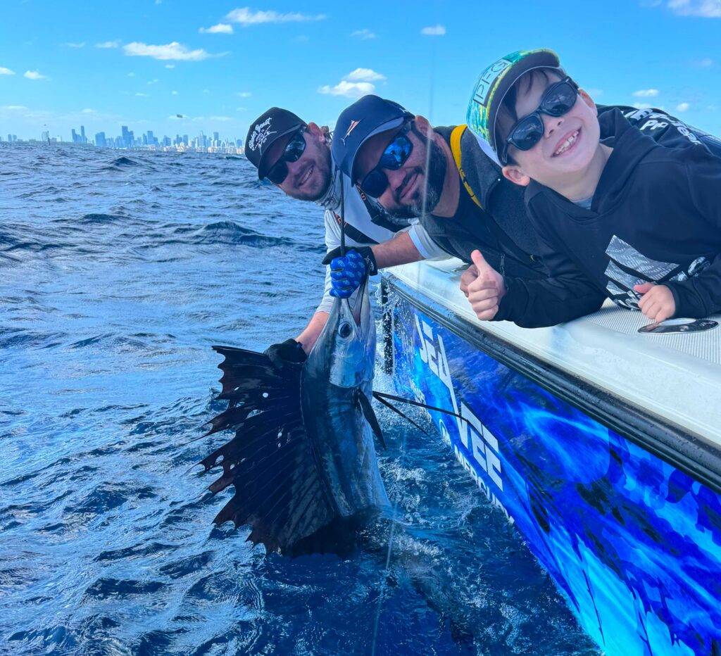 Young angler and his father releasing a sailfish with the Miami Beach skyline in the background.