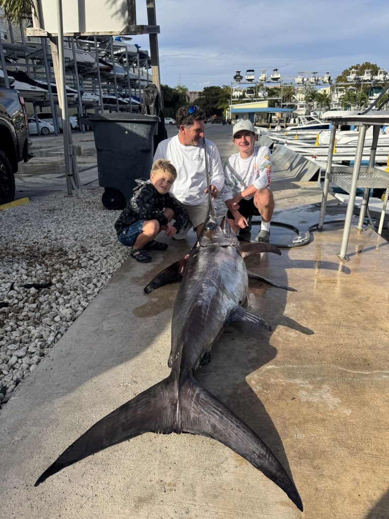 Angler and kids with a trophy swordfish at the dock
